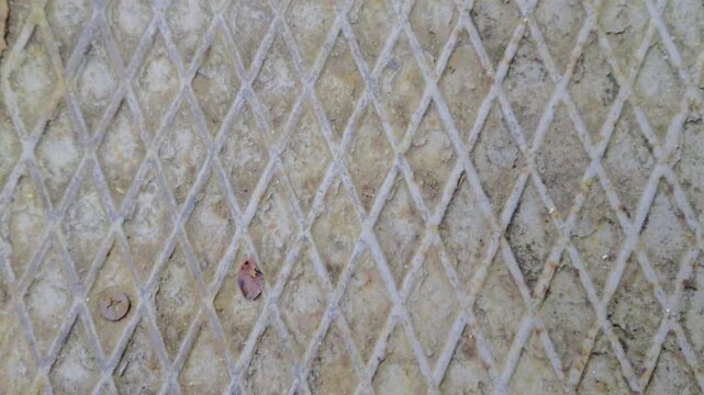 Macro view of orange oxidation on diamond plate steel featuring a non-slip safety tread pattern at an industrial site in Budapest. Professional source for 2026 sensory and tactile materiality stock.