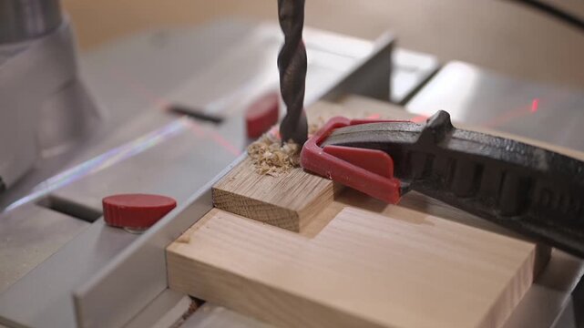 Close up video of drilling a wooden piece secured with a clamp on a workbench. Precision woodworking process, tool accuracy, DIY carpentry and safe workshop practice.