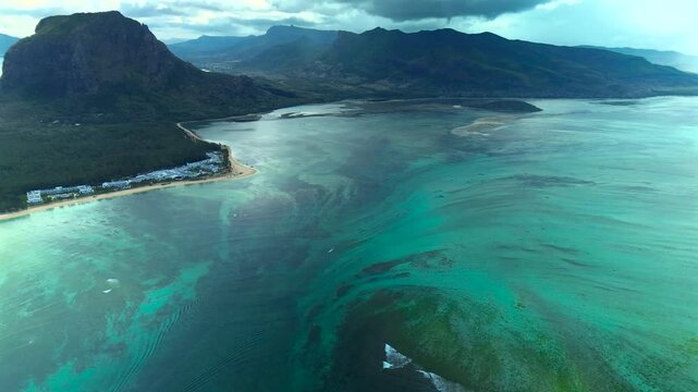 Stunning drone shot of the underwater waterfall optical illusion at Le Morne. Silt and sand deposits flow off the coastal shelf into the deep blue Indian Ocean.