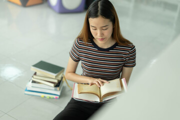Female asian student studying and reading book in library