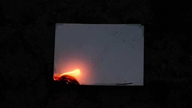 Burning and glowing photo or paper with fire flame and smoke on dark background