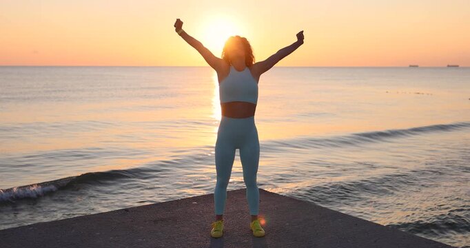 Fit woman stretching at the beach after running outdoors in the morning. Sporty female relaxing after training. Slow motion
