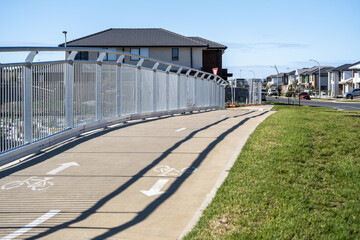 Obraz premium A bicycle lane with directional markings running through a newly developed suburban residential area in Australia. Active transport infrastructure, urban planning for cycling and biking in Point Cook