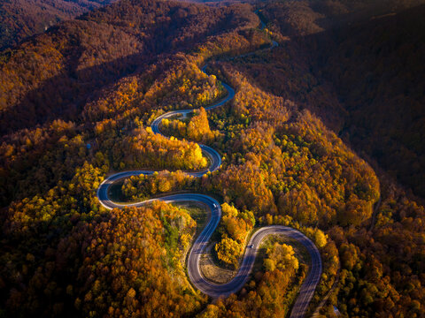 An aerial view of the winding road through a high mountain pass, passing through dense forest
