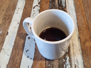 It is a mug with some coffee in it.