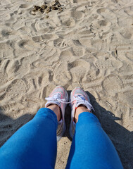 Sneakers on the sandy beach are your legs