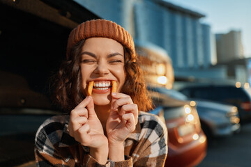Smiling woman fries playful candid beanie portrait urban authenticity candid lifestyle emotional storytelling mindful living captured at golden hour glow, joyful closeup with warm sunlight and