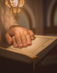 Obraz premium Man hands holding open Quran book in warm light