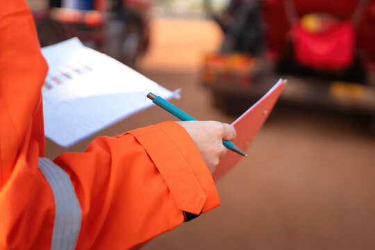 Close-up at operation supervisor hand in action of checking on the document and certification during perform safety audit at construction working site. Industrial working scene.
