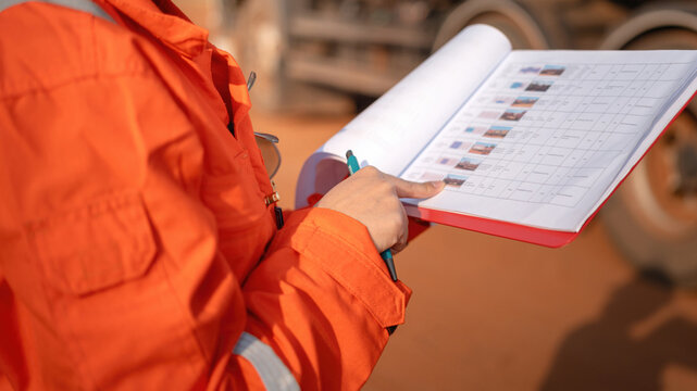 Close-up at operation supervisor hand in action of checking on the document and certification during perform safety audit at construction working site. Industrial working scene.