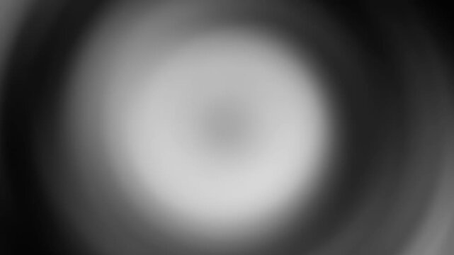 A blurred radial gradient of grayscale tones, emanating from a dark center outwards
