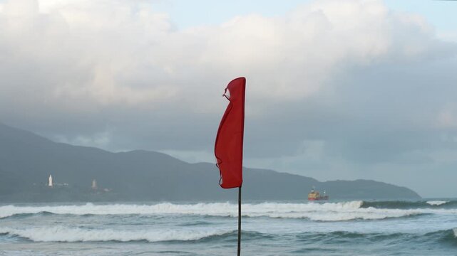 A red flag with heavy windy condition, it is the bad weather warning sign, do not swimming in the sea. Safety sign and symbol.