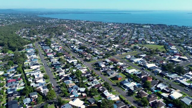 Drone aerial landscape of rural town neighbourhood streets and residential homes on suburban blocks in Killarney Vale and Tumbi Umbi with Tuggerah Lake in background Central Coast Australian tourism