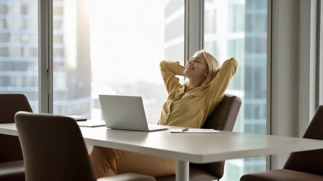 Professional woman stretching arms at desk enjoying break during modern office workday
