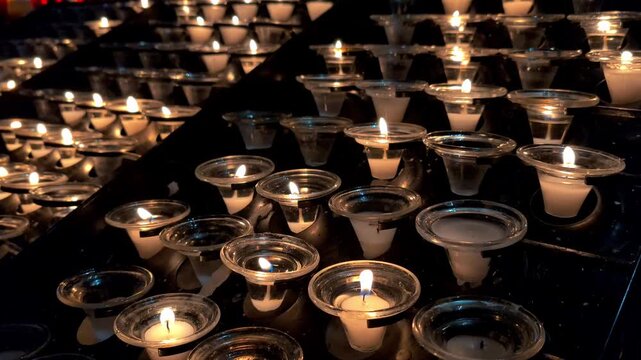 Lots of burning candles in the church. Dark background. Religious holiday and memory day concept. B-roll