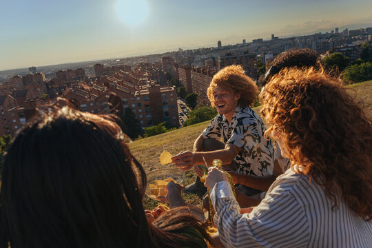 Friends enjoying sunset with chips and drinks overlooking a cityscape in Madrid