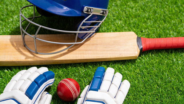 Cricket Equipment Set with Bat Ball Helmet and Gloves on Green Grass Field