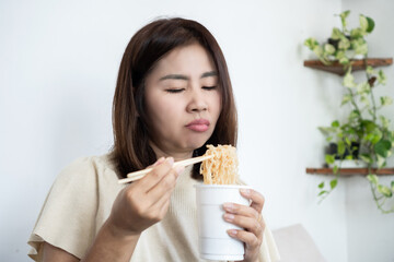Bored Asian woman with loss of appetite holding noodles. Tired mature lady feeling depressed and unwell, illustrating eating disorders, mental stress, and lack of desire to eat
