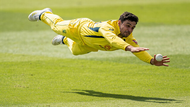 Professional Cricketer in Yellow Uniform Diving to Catch the Ball during a Match