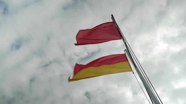 Red and yellow flags wave, warning beachgoers.