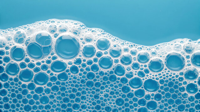 Bubbles form on a blue surface during the washing process in a household kitchen sink with warm water and detergent