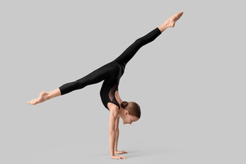 Naklejka premium Cute girl doing gymnastics on grey background
