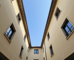 Obraz premium Upward view of beige residential buildings with multiple windows under a clear blue sky.