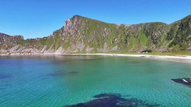 Slow turn drone flight, above sea, view on H&oslash;yvika, Hoyvika Beach, a beautiful sand beach in Vesteralen, Vester&aring;len islands in arctic Norway. Beach surrounded with grassy mountains. Amazing nature, tr
