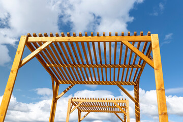 a wooden frame made of logs on the beach against a sky with clouds, part of a wooden frame building under construction to create a good infrastructure for recreation, a canopy made of planks