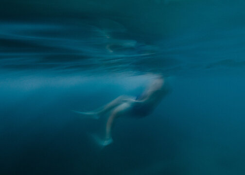 blurry photo of a woman underwater with fins