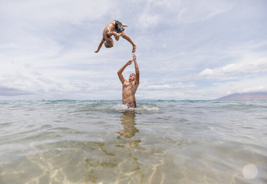 brother throwing up his little brother in the ocean