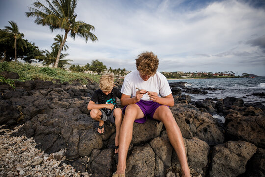 brothers looking down while sitting on a rock
