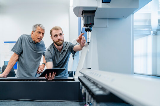 Machine operator examining machine at factory