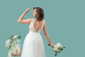 Beautiful bride in wedding dress with flowers on green background, back view