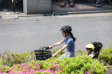 道路を自転車に乗るママと子供　ママチャリでお出かけや出勤、保育園の送迎など