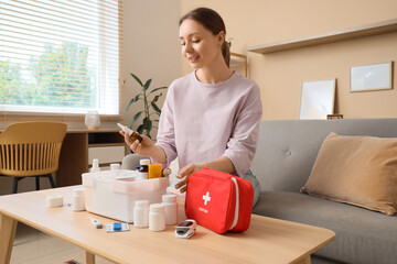 Young woman taking nasal drops from first aid kit at home