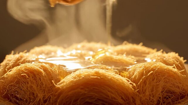 Pouring sweet golden syrup over hot, steaming Kunafa dessert