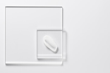 White cosmetic skin care product on glass. White background. Copy space