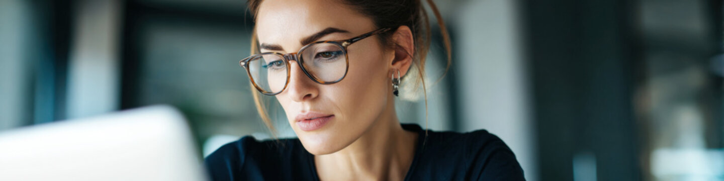 Focused caucasian female adult reading glasses studying laptop work