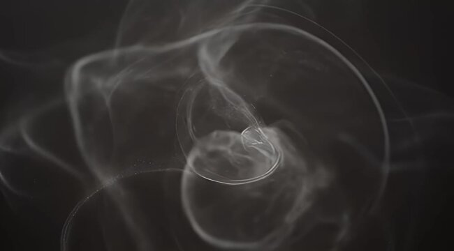 Abstract swirling smoke pattern on a dark background with delicate trails