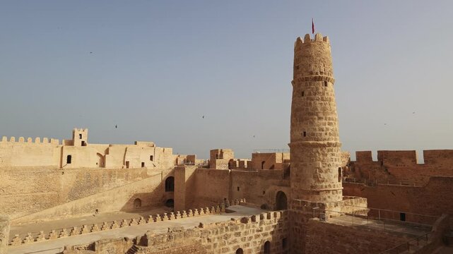 Sun-drenched historical Ribat in Monastir, traditional medieval North African fortified enclosure for religious warriors, with well-preserved stone architectural details and central tower, Tunisia