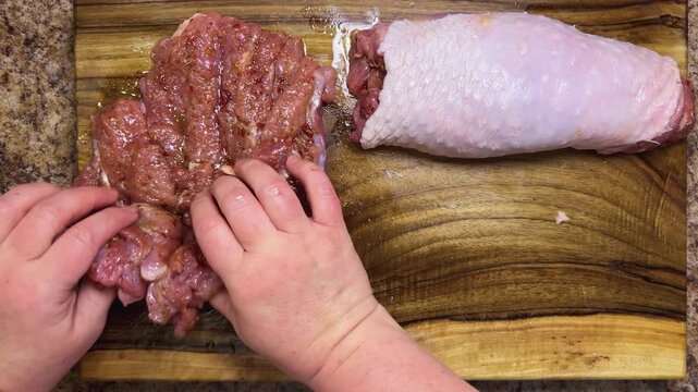Preparing the turkey thigh for the roulade. The process: hand-roll the prepared piece of meat with spices on a wooden board.