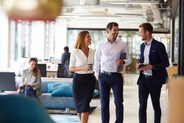 Obraz premium Contemporary open office with smiling professionals discussing ideas, sleek furniture, bright interior, productive work environment