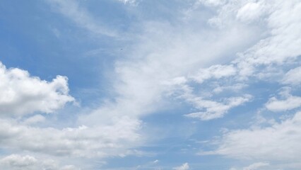 Obraz premium White fluffy clouds against a clear blue summer sky. Natural blue sky background with calm atmosphere. Blue sky texture background with soft and beautiful pattern.