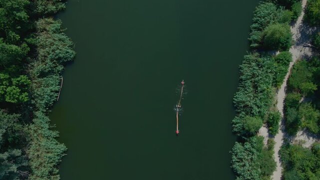 Aerial drone view of children floating on a log in the river and jumping into the water. Summer outdoor leisure and entertainment.