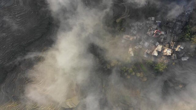 Static overhead drone shot of mist covered mountain village set in spectacular terraced rice fields in Yuanyang, Southern China