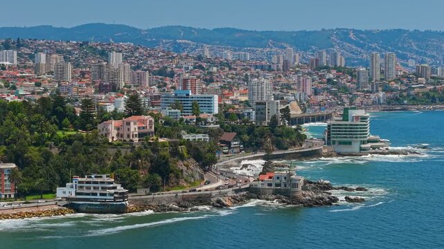 Telephoto aerial view of La Marina Avenue, the Cerro Castillo presidential palace, and Castillo Wulff on a sunny day with good waves in Vi&ntilde;a del Mar, Chile.
