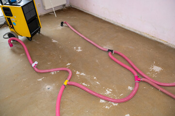 Floor drying after a burst water pipe using a dehumidifier with water damage restoration pipes