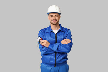 Portrait of male electrician with multimeter on grey background
