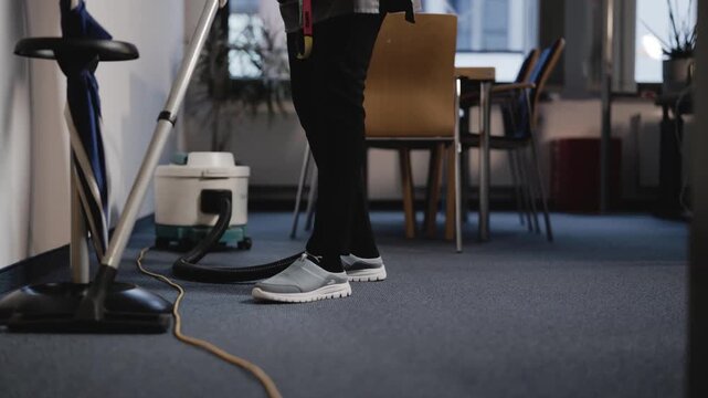 Reinigungskraft saugt den B&uuml;roteppich